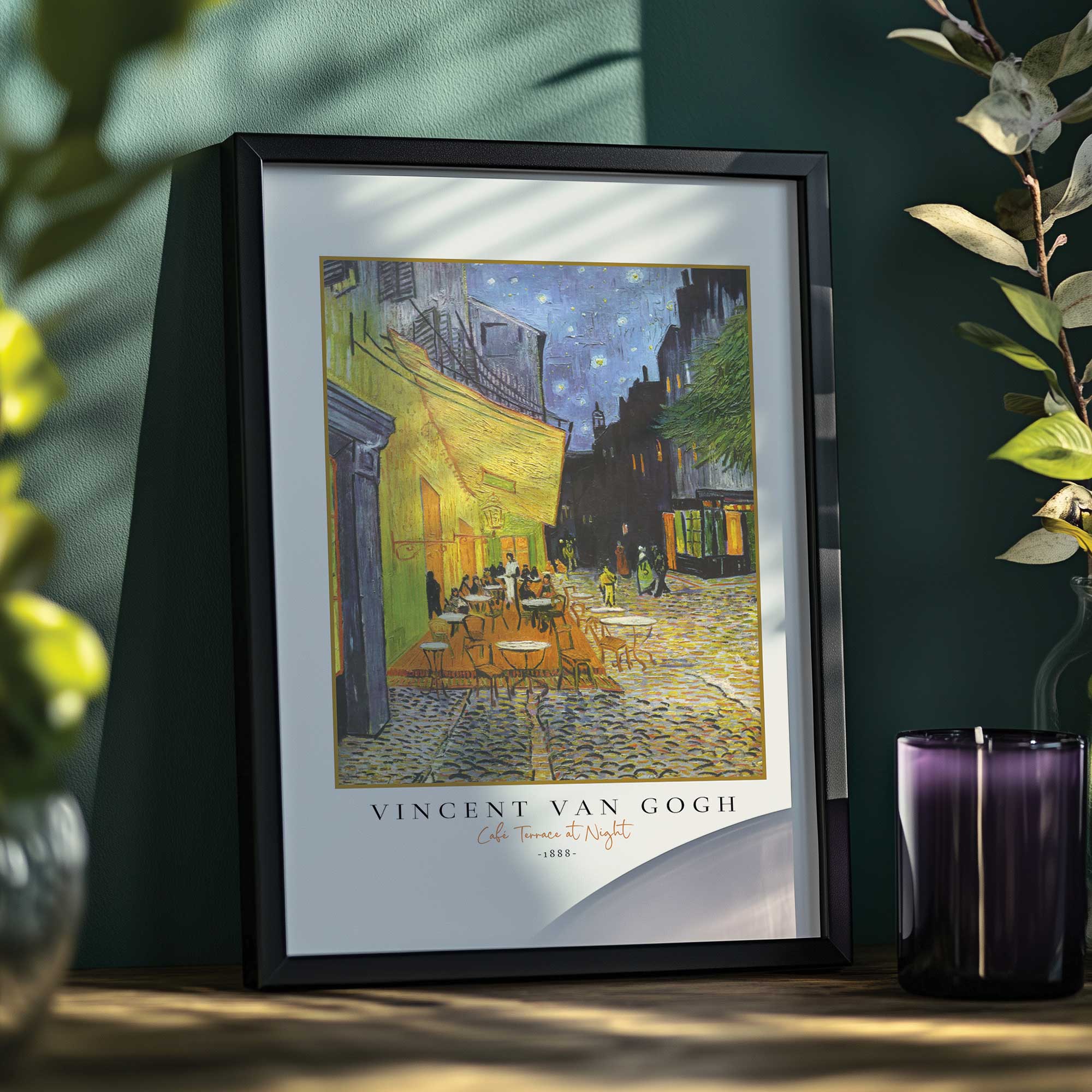 van gogh's café terrace at night print in a black frame on a desk