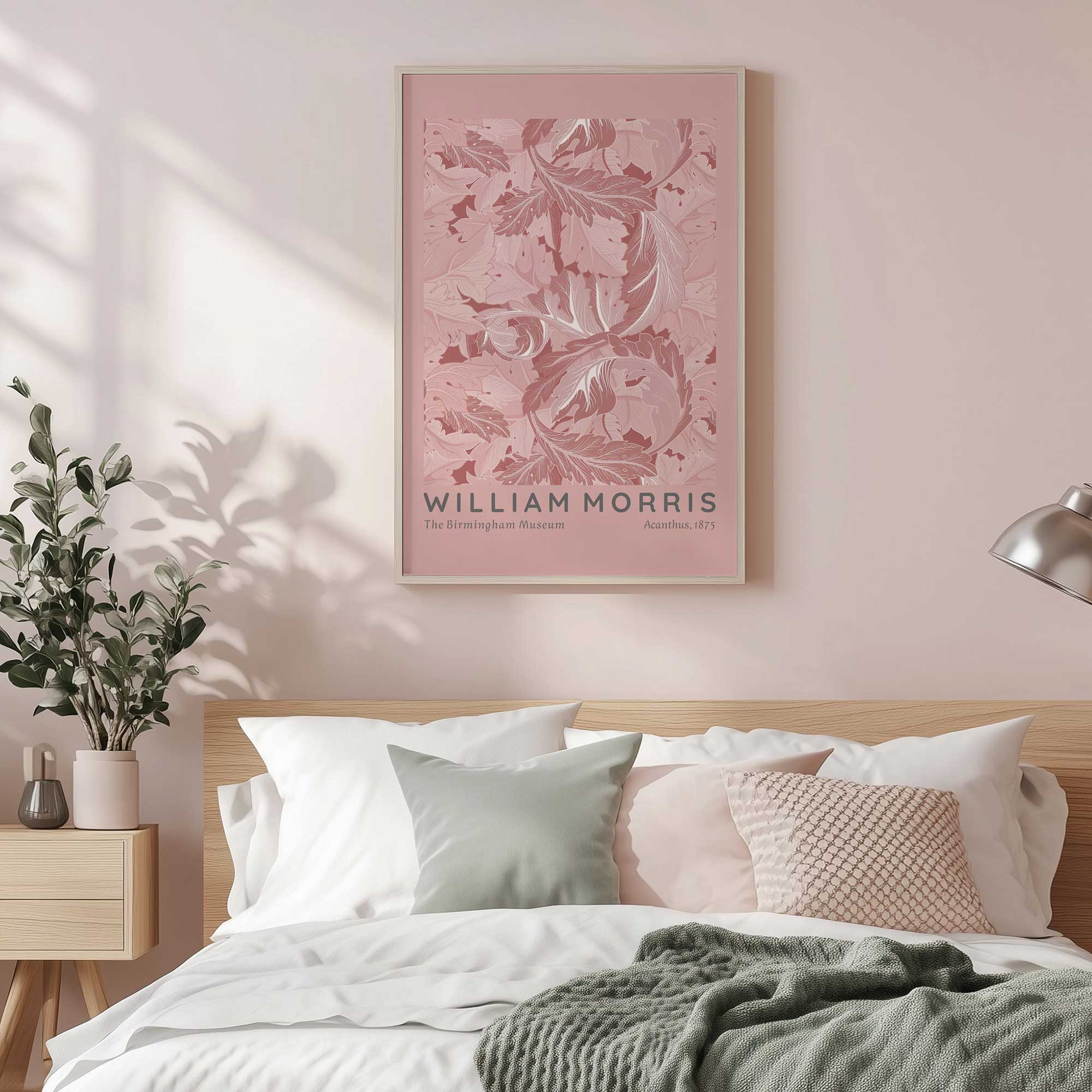 Blush acanthus by William Morris in a white frame hanging above a bed with blush cushions on it