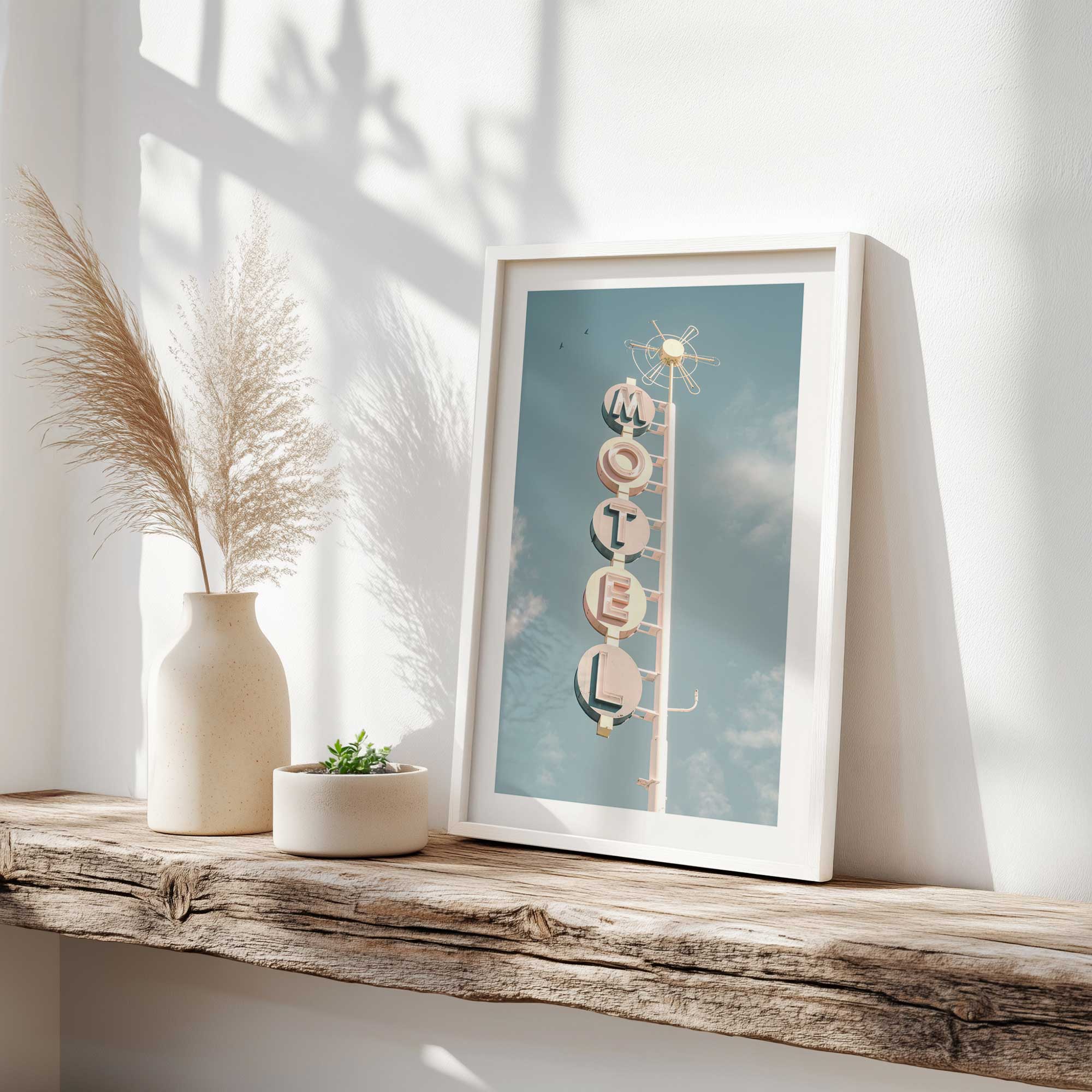 retro motel glow up print of vintage motel sign in a white frame on a driftwood shelf