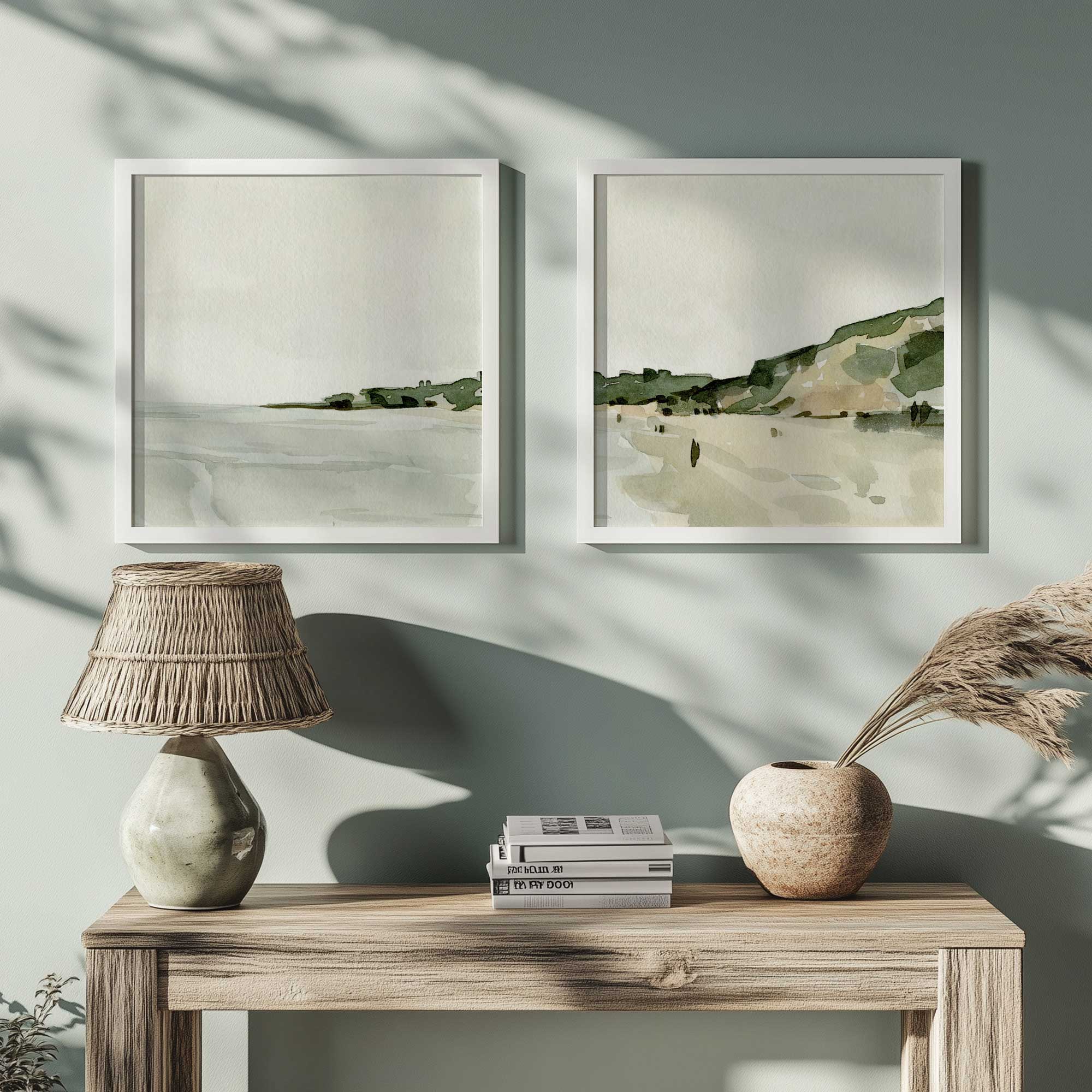 soft coastal views set of 2 prints hanging above a consle table with pampas grass, books and a table lamp with a rattan lamp shade